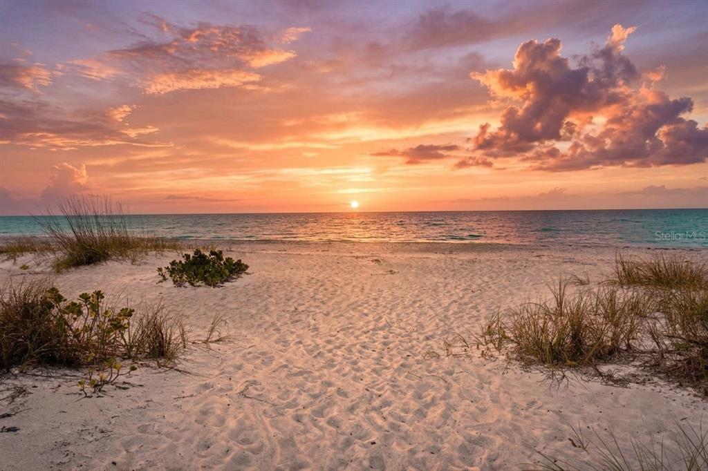 A sandy beach path leads toward the ocean under a vibrant sunset sky — 793 JUNGLE QUEEN WAY, LONGBOAT KEY, FL