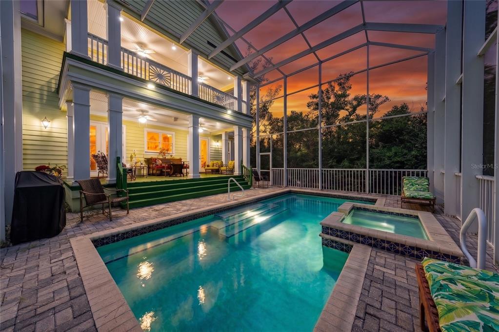 A two-story house with a screened-in pool, hot tub, and covered patio at sunset — 793 JUNGLE QUEEN WAY, LONGBOAT KEY, FL