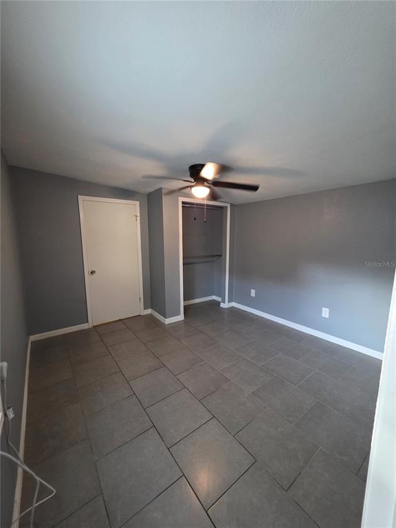 A bedroom with gray walls, large square floor tiles, a ceiling fan, and a closet — 1328 37TH STREET NW, WINTER HAVEN, FL
