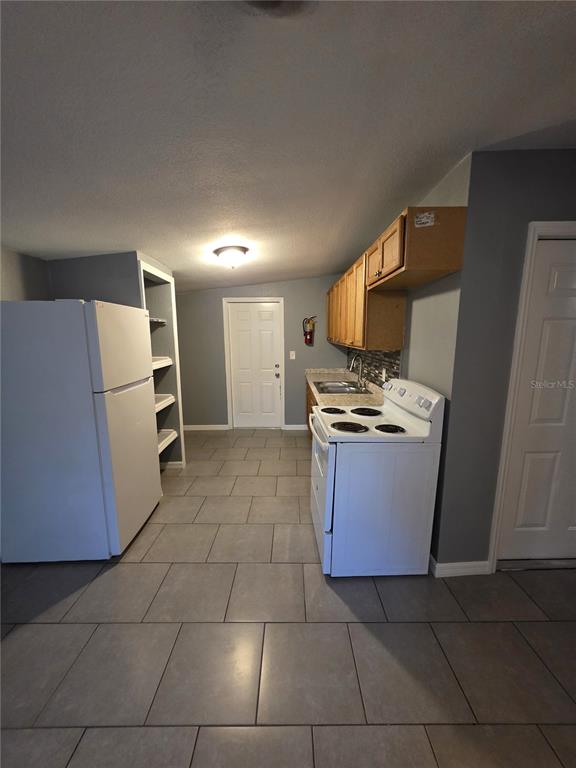 A kitchen features a white refrigerator, a white electric stove, and light-colored wooden cabinets — 1328 37TH STREET NW, WINTER HAVEN, FL