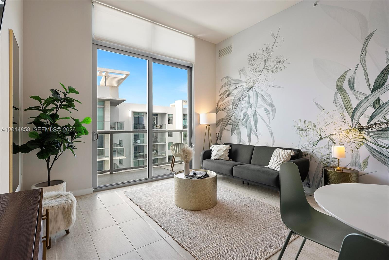 A modern living room features a dark sofa, a mural wall, and a balcony view — 3900 Biscayne Blvd, Miami FL 33137, MIAMI, FL