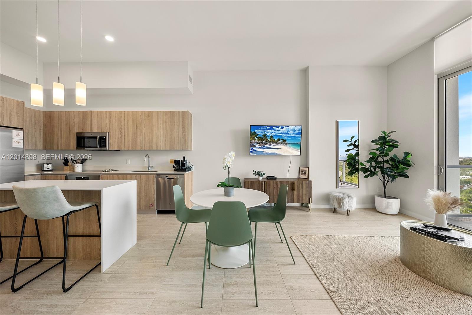 An open-concept kitchen and dining area features light wood cabinetry, a white island, and balcony — 3900 Biscayne Blvd, Miami FL 33137, MIAMI, FL
