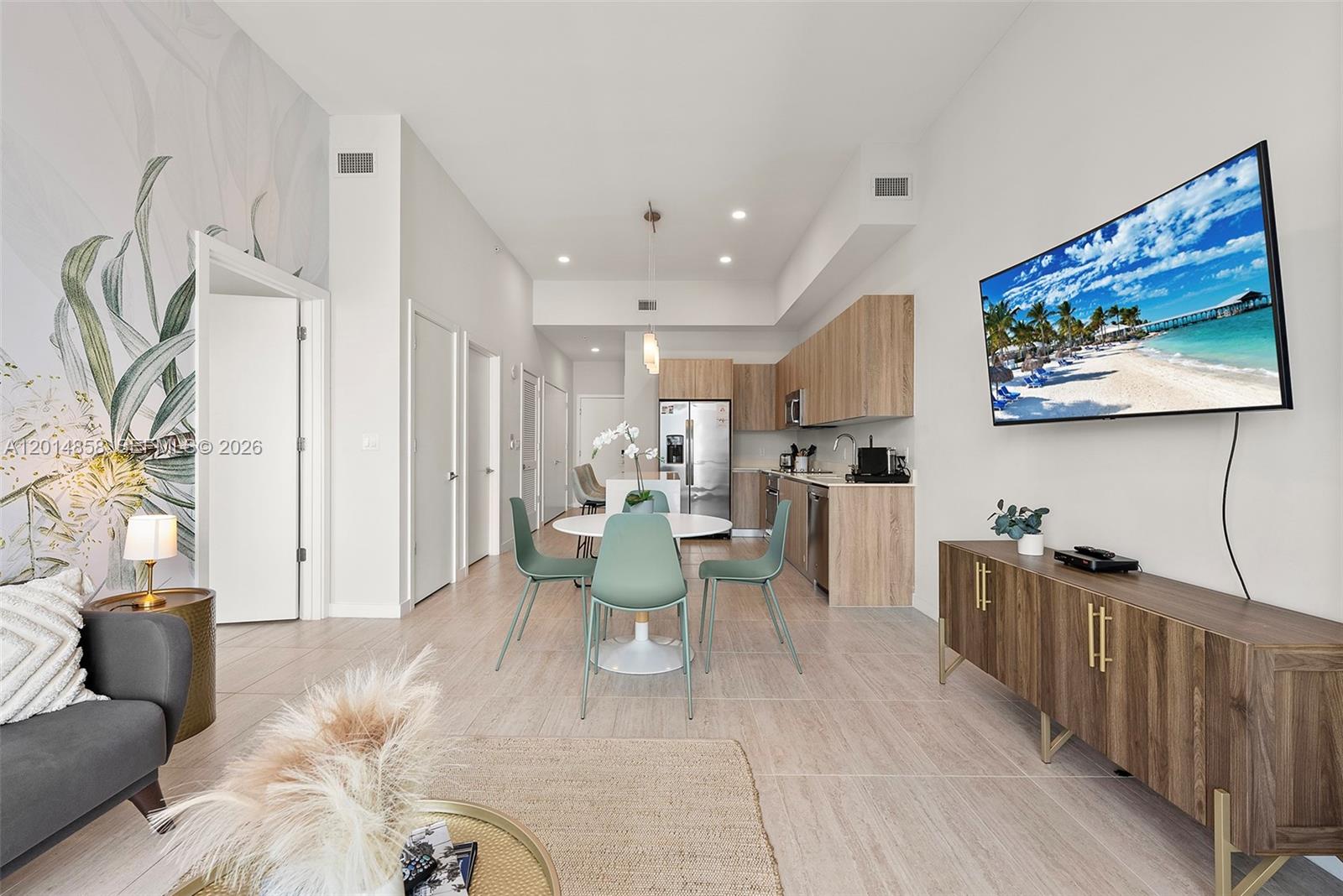 A modern open-concept living and dining area features light wood cabinetry and a wall-mounted television — 3900 Biscayne Blvd, Miami FL 33137, MIAMI, FL