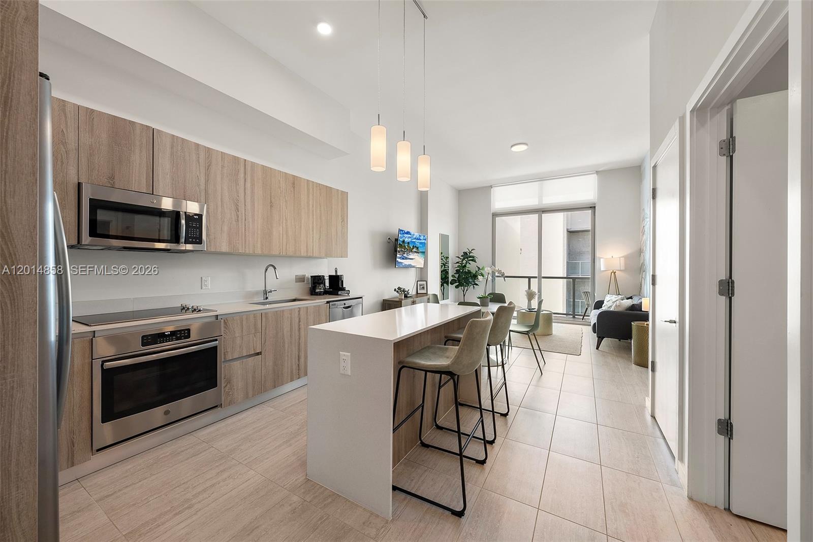 A modern kitchen features light wood cabinetry, stainless steel appliances, and a central island — 3900 Biscayne Blvd, Miami FL 33137, MIAMI, FL