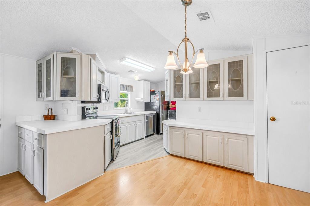 A kitchen with light-colored cabinets, white countertops, a dining area, and wood-look flooring — 7225 MOUNT FAIRFIELD ROAD NE UNIT 541, ST PETERSBURG, FL
