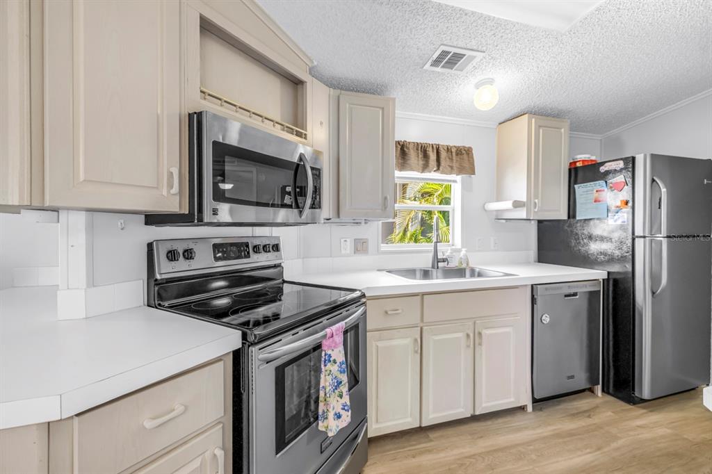 A kitchen with light-colored cabinets, stainless steel appliances, white countertops, and wood-look flooring — 7225 MOUNT FAIRFIELD ROAD NE UNIT 541, ST PETERSBURG, FL
