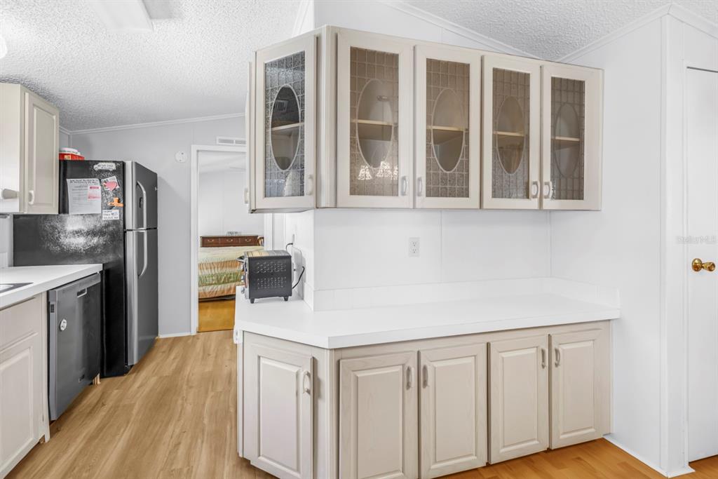A kitchen features light-colored cabinets, white countertops, a black refrigerator, and wood-look flooring — 7225 MOUNT FAIRFIELD ROAD NE UNIT 541, ST PETERSBURG, FL