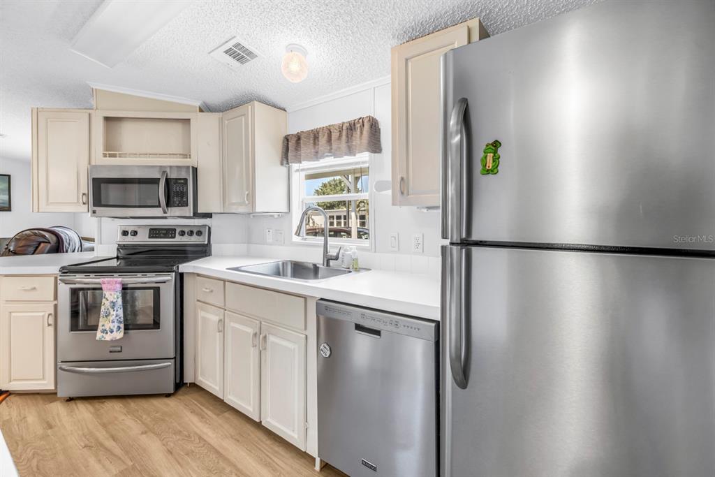 A kitchen features stainless steel appliances, light-colored cabinets, and wood-look flooring — 7225 MOUNT FAIRFIELD ROAD NE UNIT 541, ST PETERSBURG, FL