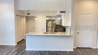 A kitchen features a breakfast bar, stainless steel refrigerator, and light-colored cabinetry — 7270 WESTPOINTE BOULEVARD UNIT 933, ORLANDO, FL