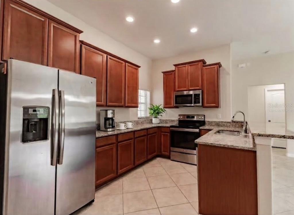 A kitchen with wood cabinets, stainless steel appliances, and granite countertops — 18591 BRIAR OAKS DRIVE, HUDSON, FL