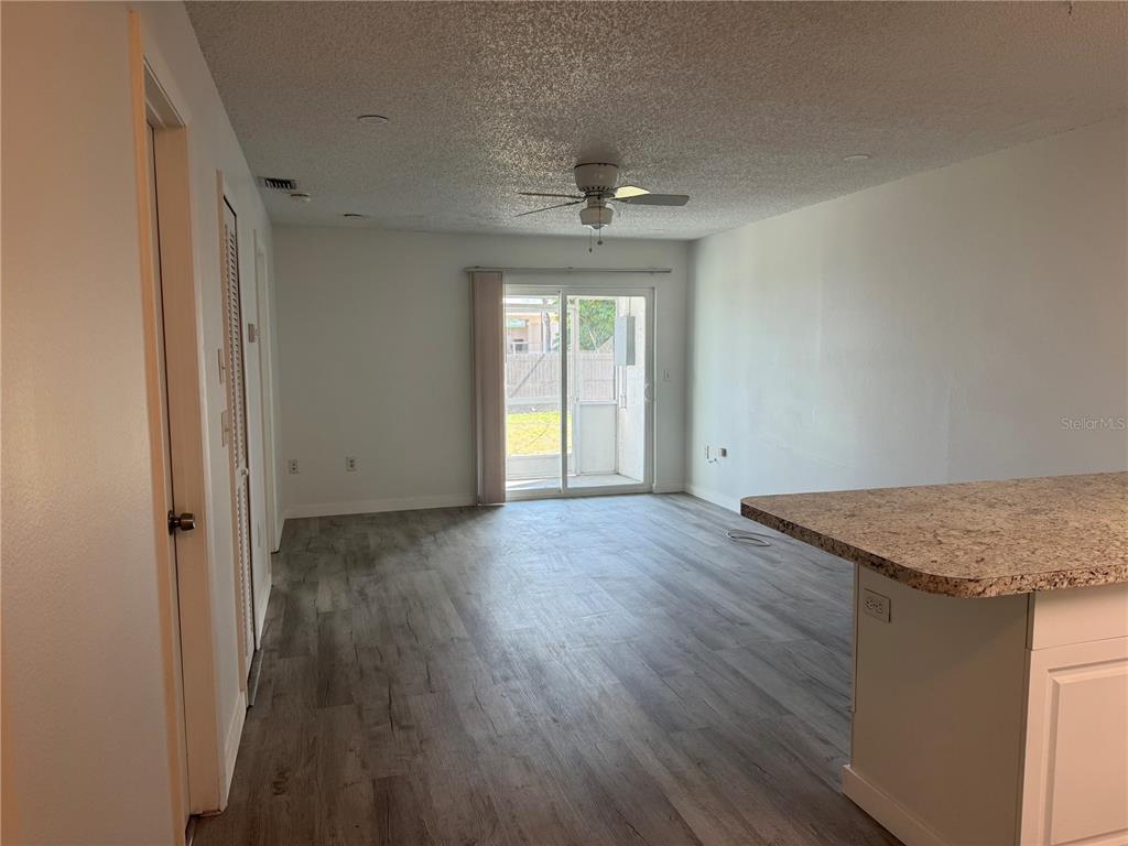 An open-concept living area features wood-look flooring, a ceiling fan, and sliding glass patio doors — 6428 HAMLET DRIVE UNIT A, ENGLEWOOD, FL