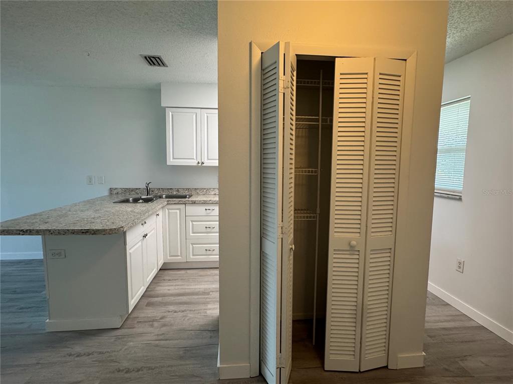 A kitchen with granite countertops and white cabinets sits next to a louvered-door pantry — 6428 HAMLET DRIVE UNIT A, ENGLEWOOD, FL