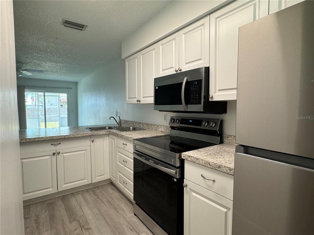 A kitchen features white cabinets, stainless steel appliances, and granite countertops with a breakfast bar — 6428 HAMLET DRIVE UNIT A, ENGLEWOOD, FL