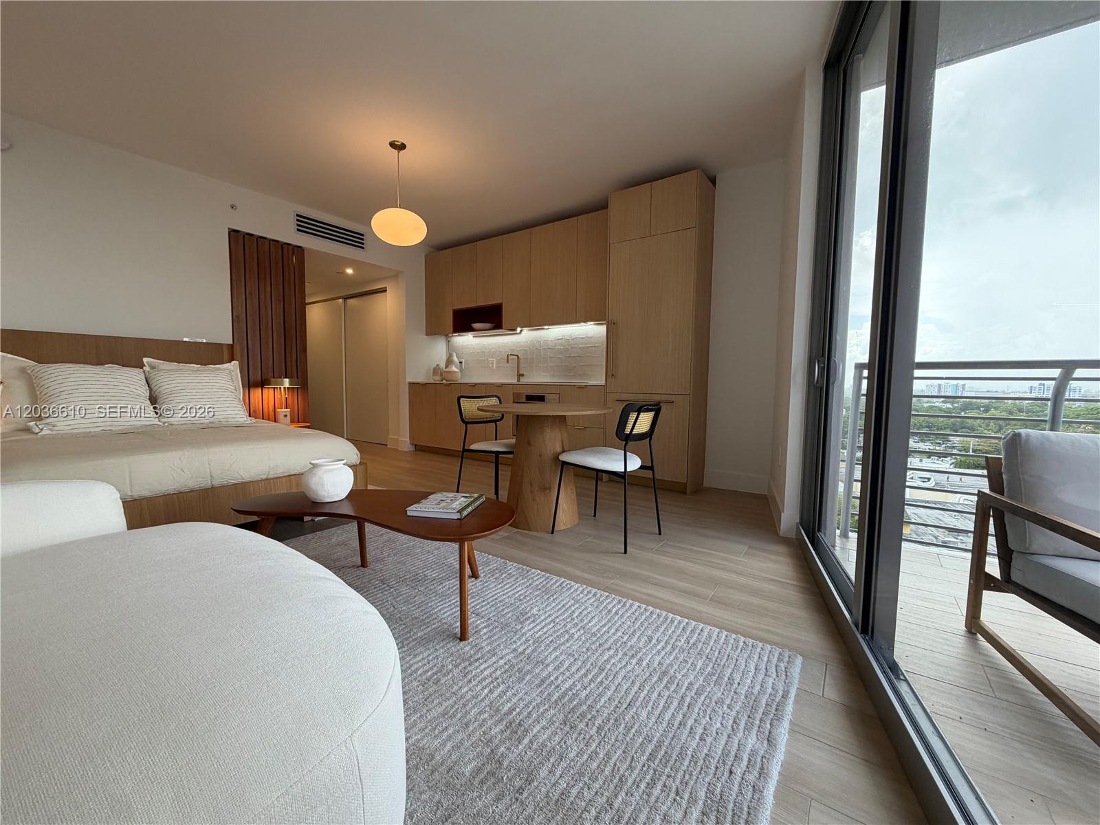 A studio apartment features a kitchenette, a bed, and a balcony with an outdoor view — 90 NE 32 # 1014, Miami FL 33149, MIAMI, FL