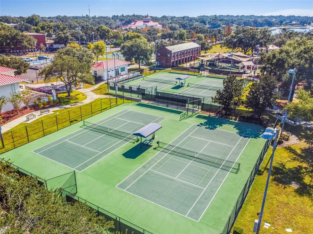 An aerial view shows two fenced tennis courts with shaded benches next to a park — 518 INGLESIDE LANE, HAINES CITY, FL