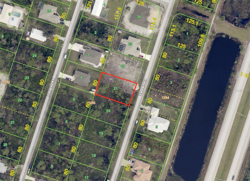 A vacant, grassy lot with scattered trees and a nearby house under a blue sky — 3419 VESSELS ROAD, PORT CHARLOTTE, FL