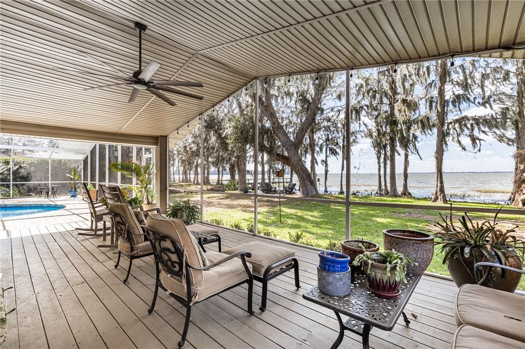 A screened-in porch with a ceiling fan, wood-look flooring, and a view of a lake — 11322 DEAD RIVER ROAD, TAVARES, FL