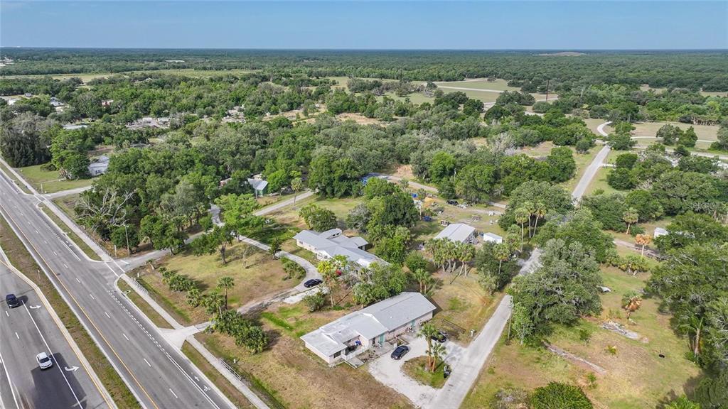 An aerial view shows two houses on a large, tree-filled lot next to a highway — 1870 SW PAX DUCES DRIVE E UNIT 1868, ARCADIA, FL