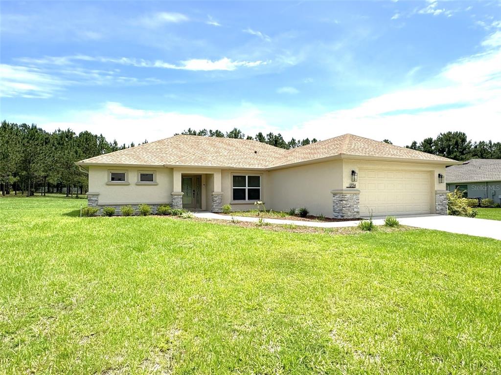 A single-story house with a tan stucco exterior, stone accents, and a two-car garage — 1724 E GATE DANCER CIRCLE, INVERNESS, FL