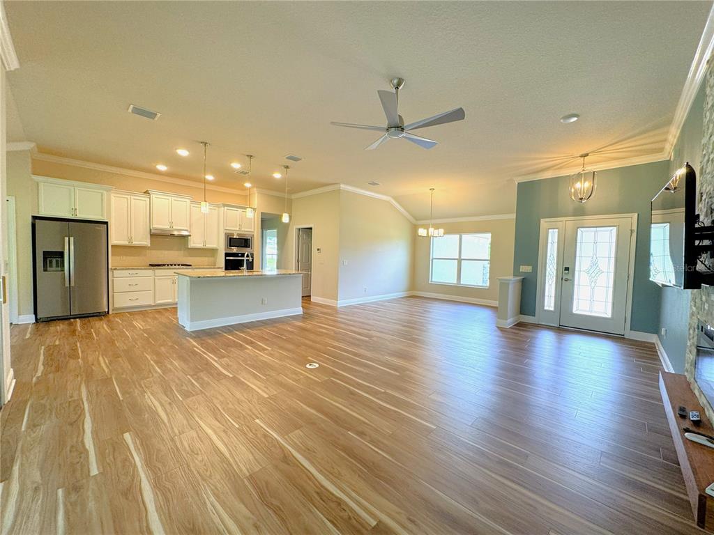 An open-concept living area features a kitchen with white cabinets, wood-look flooring, and vaulted ceilings — 1724 E GATE DANCER CIRCLE, INVERNESS, FL