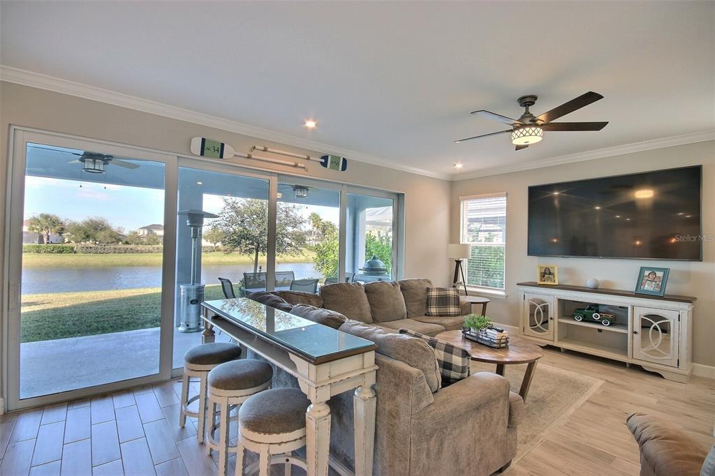 A living room features a sectional sofa, a console table, and sliding doors overlooking water — 10563 PIEDRA DR, PALMETTO, FL