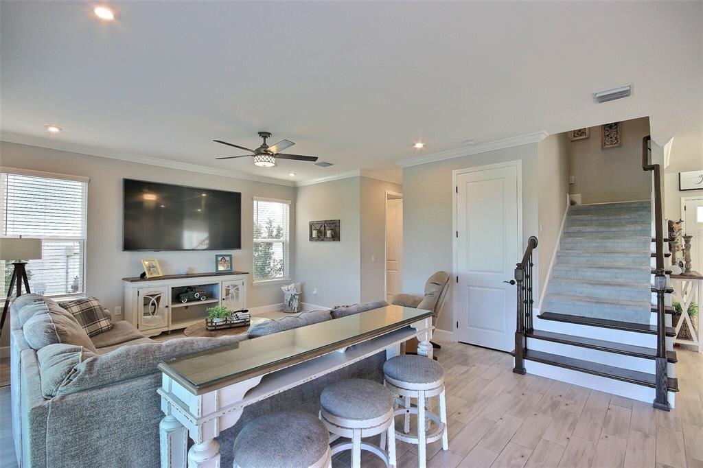 A living room features a sofa, a console table with stools, and a carpeted staircase — 10563 PIEDRA DR, PALMETTO, FL