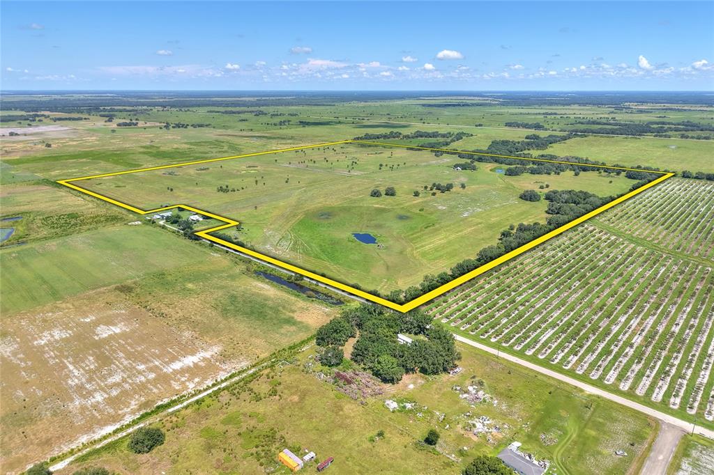 An aerial view shows a large, fenced-in grassy pasture with a small pond and trees — NW LIMESTONE HEIGHTS STREET, ARCADIA, FL