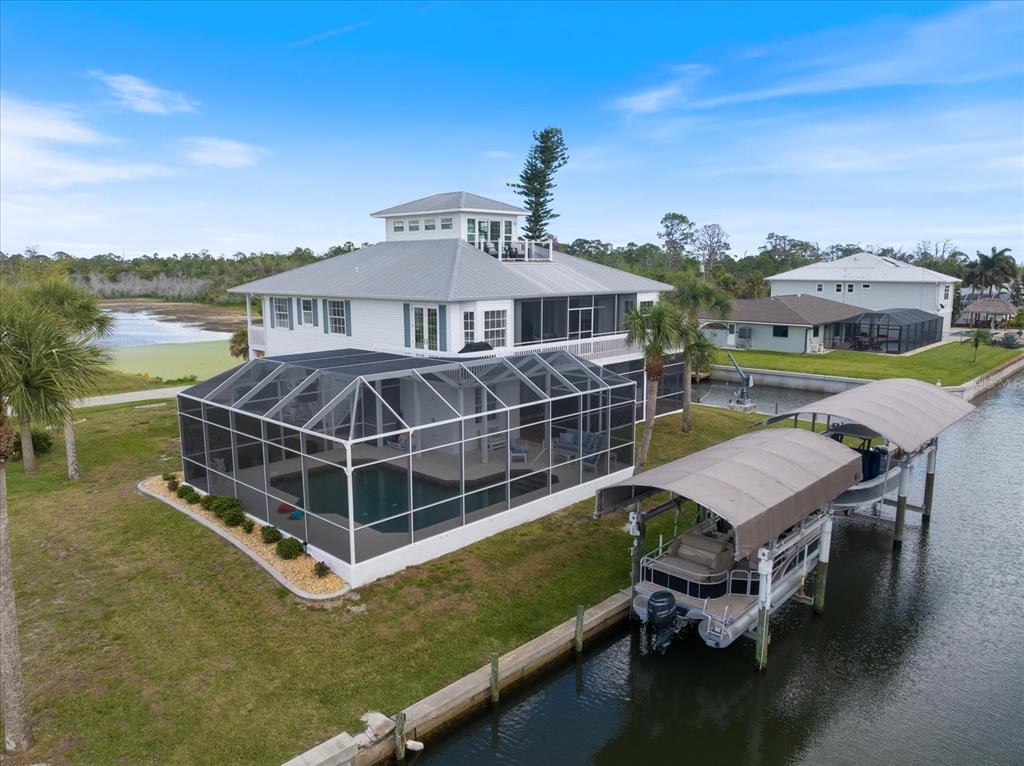 An aerial view of a waterfront house with a screened pool enclosure and boat lifts — 9181 LAKE DRIVE, ENGLEWOOD, FL