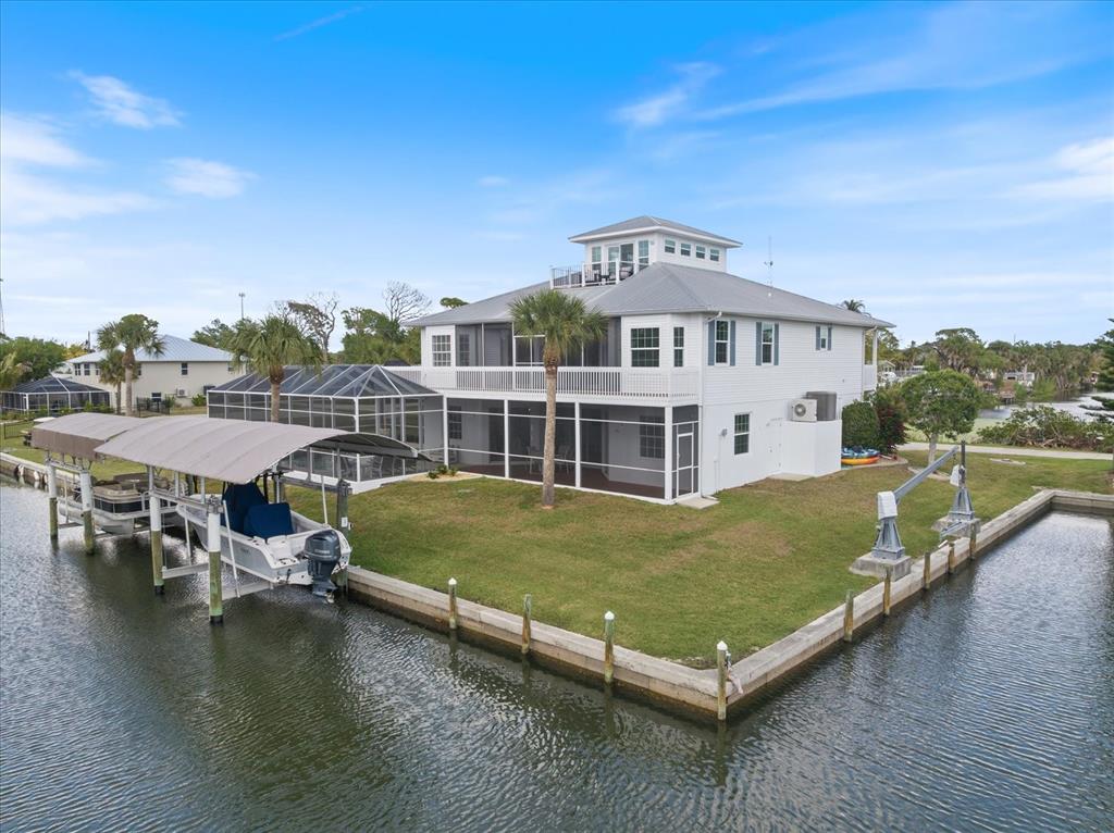 A white two-story house with a screened porch and boat lift sits on a canal — 9181 LAKE DRIVE, ENGLEWOOD, FL