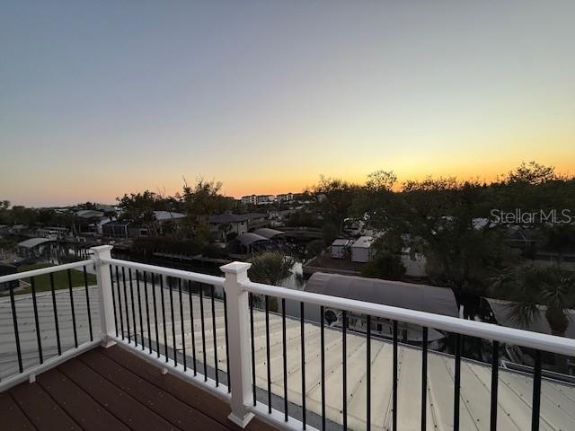 An elevated wooden deck with white railings overlooks a canal and residential neighborhood at sunset — 9181 LAKE DRIVE, ENGLEWOOD, FL