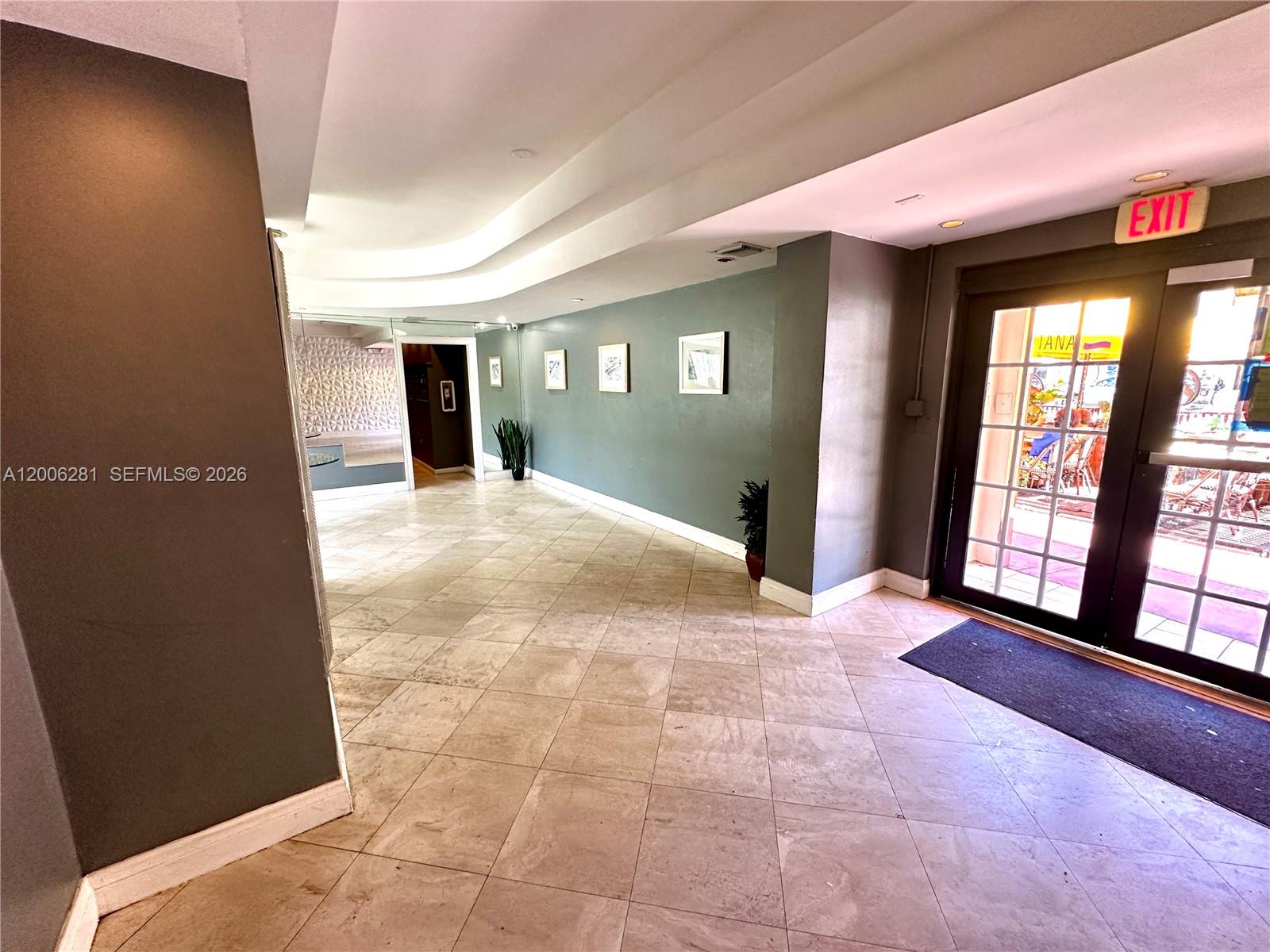 This lobby features tiled floors, a gray accent wall with framed art, and glass doors — 710 Washington Ave # 321, Miami Beach FL 33139, MIAMI BEACH, FL
