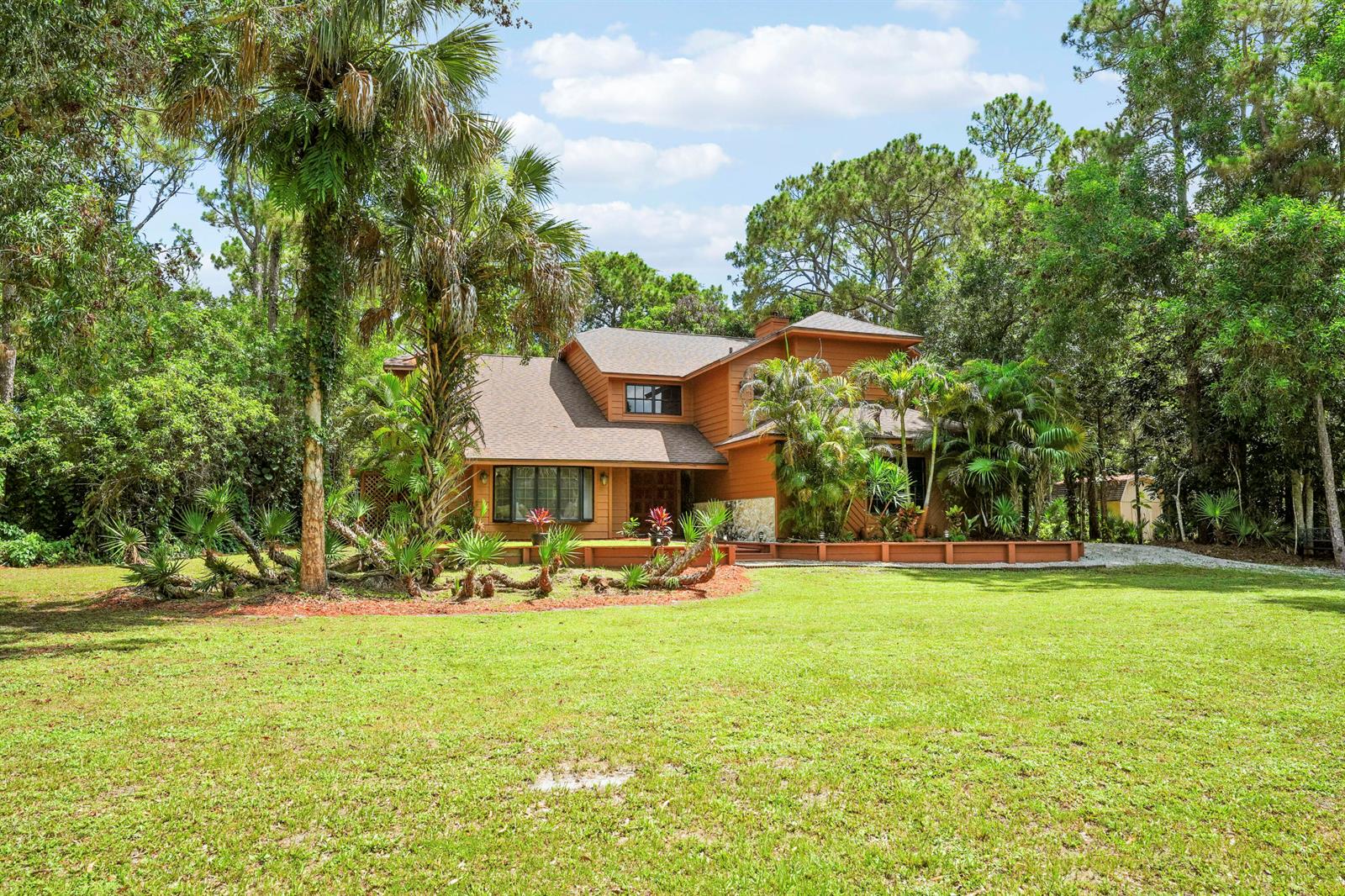 A two-story brown house with a large lawn surrounded by dense trees and palm plants — 12613 189th Court N, Jupiter FL 33478, JUPITER, FL
