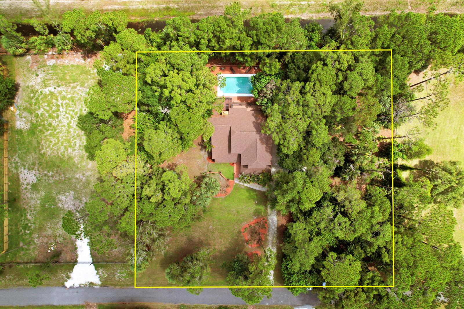 An aerial view shows a house with a swimming pool surrounded by dense trees — 12613 189th Court N, Jupiter FL 33478, JUPITER, FL
