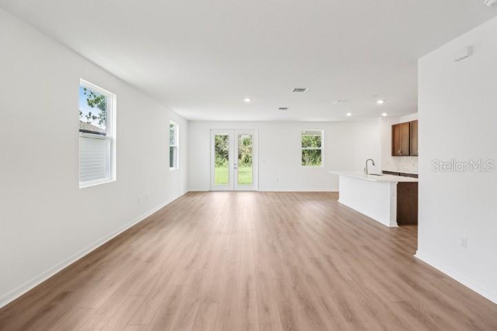 An open-concept living area features light wood-look flooring, white walls, and a kitchen island — 17637 LAKE STAR ROAD, WINTER GARDEN, FL