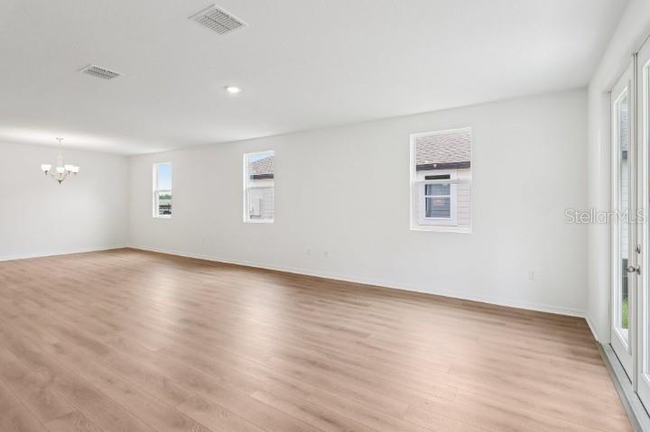 An open-concept room with light wood-look flooring, white walls, recessed lighting, and a chandelier — 17637 LAKE STAR ROAD, WINTER GARDEN, FL