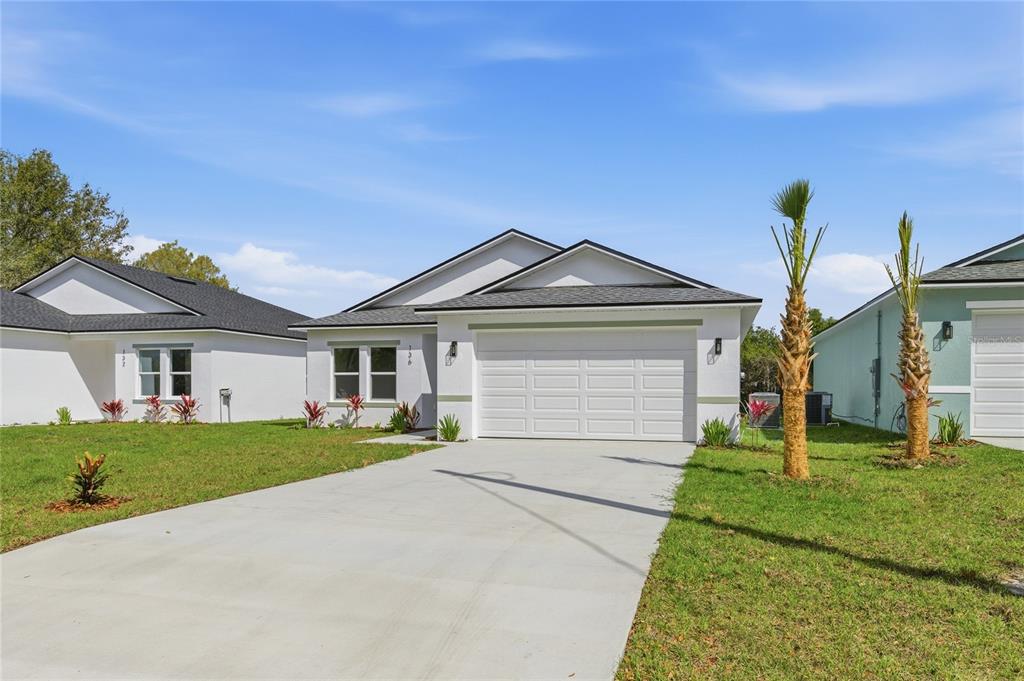 A single-story house with a white exterior, a two-car garage, and a concrete driveway — 136 11TH AVENUE, OSTEEN, FL