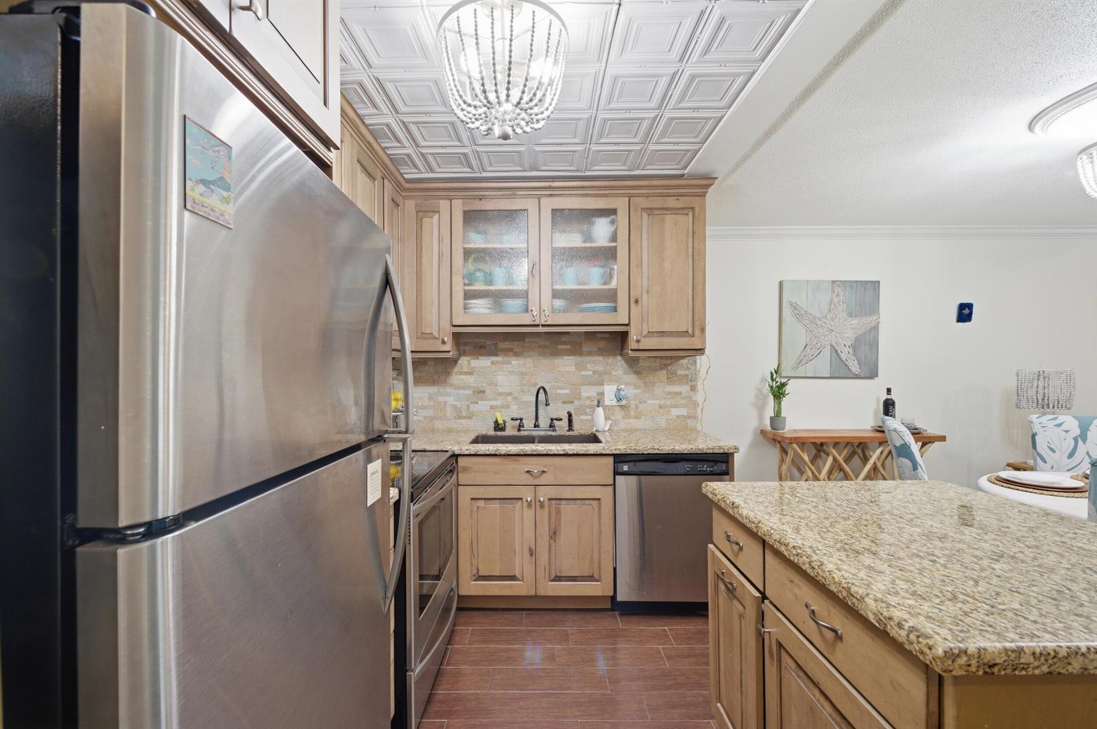 A kitchen features wood cabinets, granite countertops, stainless steel appliances, and a decorative ceiling — 101 E Mcnab Road # 102, Pompano Beach FL 33060, POMPANO BEACH, FL