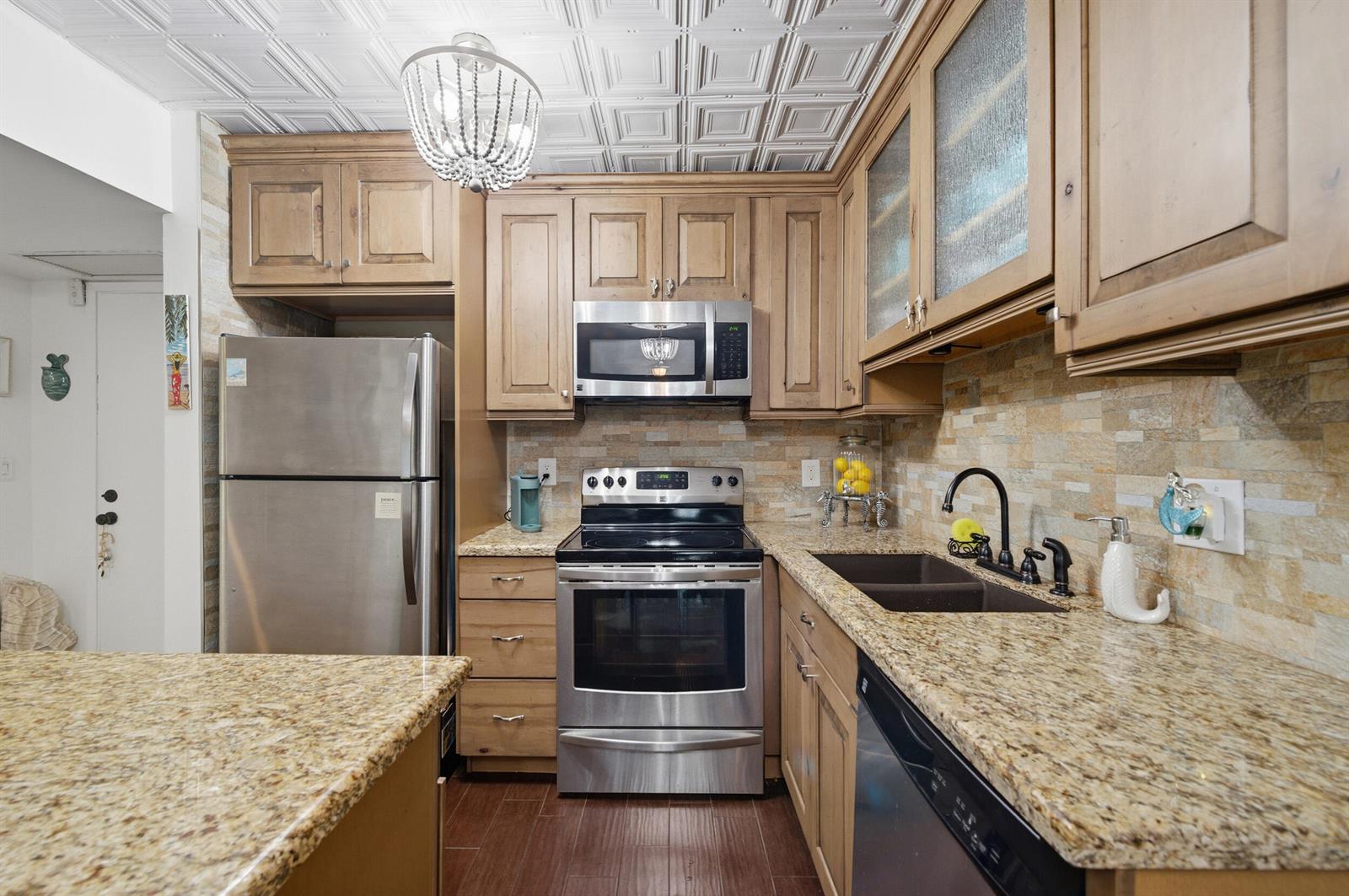 A kitchen features wood cabinets, granite countertops, stainless steel appliances, and a decorative ceiling — 101 E Mcnab Road # 102, Pompano Beach FL 33060, POMPANO BEACH, FL