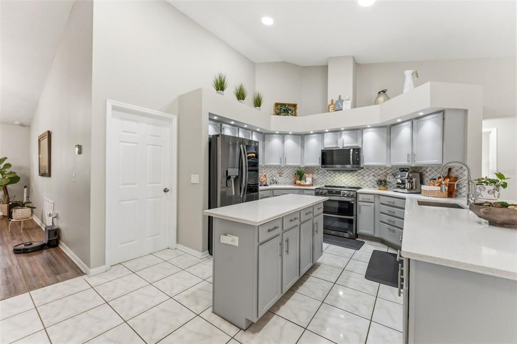 A kitchen with gray cabinets, a central island, white countertops, and light tile flooring — 19906 JODI DRIVE, LUTZ, FL