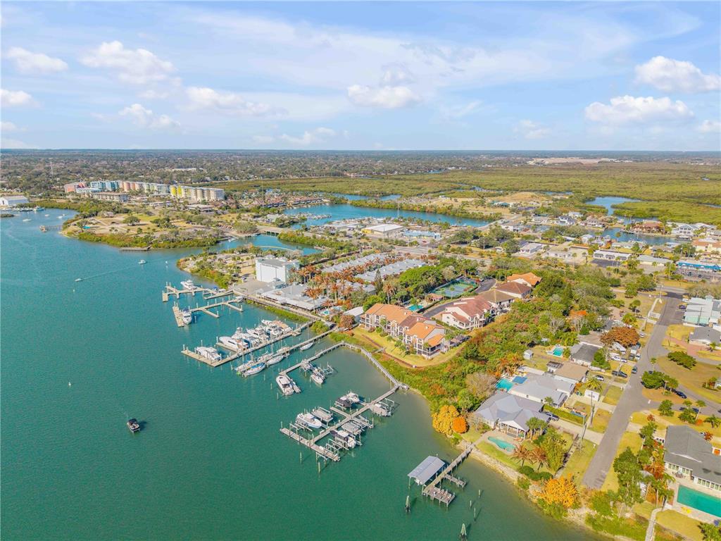 An aerial view shows a marina with docked boats adjacent to waterfront residential buildings — 135 MARINA BAY DRIVE, NEW SMYRNA BEACH, FL