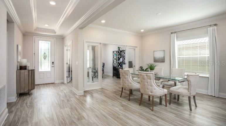 A dining room with light wood flooring, a glass table, and chairs near a doorway — 49 VINCA STREET, HOMOSASSA, FL