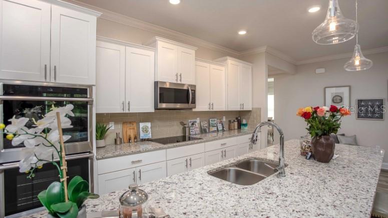 A kitchen features white cabinets, granite countertops, a double wall oven, and a center island — 49 VINCA STREET, HOMOSASSA, FL