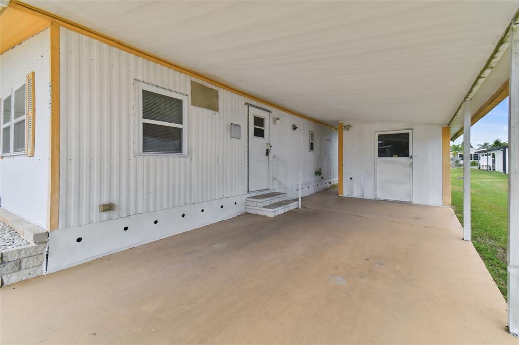 A side view of a mobile home featuring a covered carport and a concrete driveway — 5353 COMANCHE STREET, ZEPHYRHILLS, FL