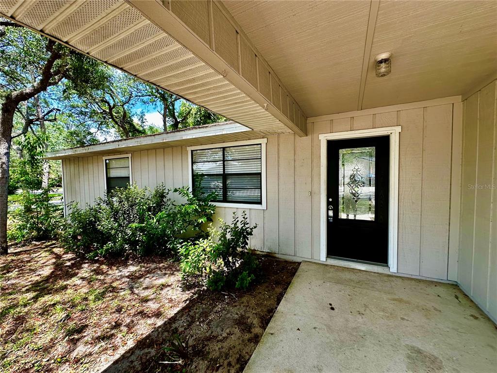 The exterior of a house features a concrete porch, a black front door, and siding — 4 BLACK JACK CIRCLE, PORT ORANGE, FL