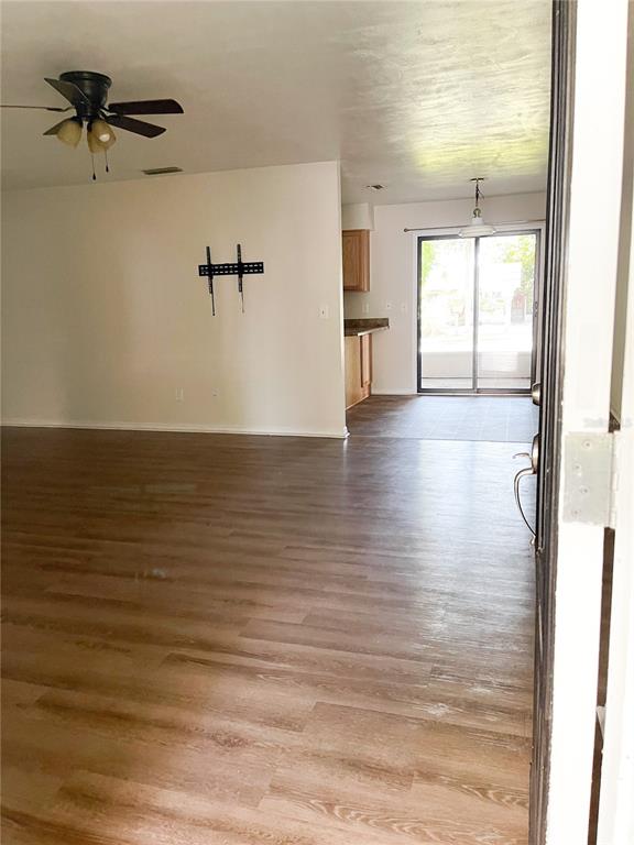 An open-concept living area features wood-look flooring, a ceiling fan, and a sliding glass door — 4 BLACK JACK CIRCLE, PORT ORANGE, FL