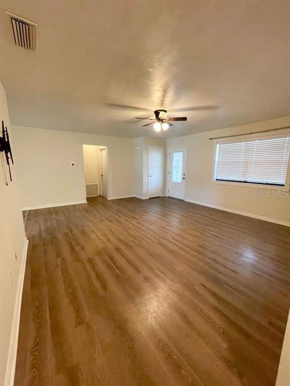 An empty living room features light-colored walls, wood-look flooring, a ceiling fan, and a window — 4 BLACK JACK CIRCLE, PORT ORANGE, FL