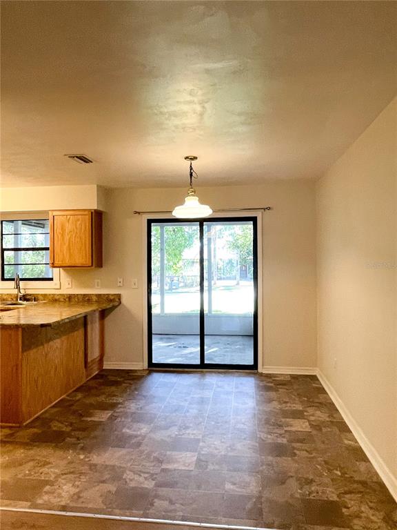 A kitchen with wooden cabinets and a dining area featuring a sliding glass door — 4 BLACK JACK CIRCLE, PORT ORANGE, FL