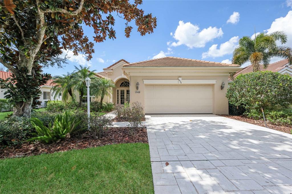 A single-story house with a beige stucco exterior, a two-car garage, and a paved driveway — 8428 MISTY MORNING COURT, LAKEWOOD RANCH, FL