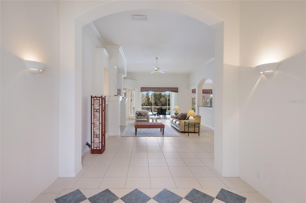 A tiled entryway leads through an arched opening into a living room with a view — 8428 MISTY MORNING COURT, LAKEWOOD RANCH, FL