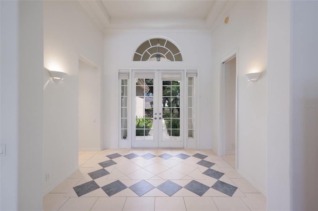 A bright foyer features white walls, a tiled floor with a diamond pattern, and double doors — 8428 MISTY MORNING COURT, LAKEWOOD RANCH, FL